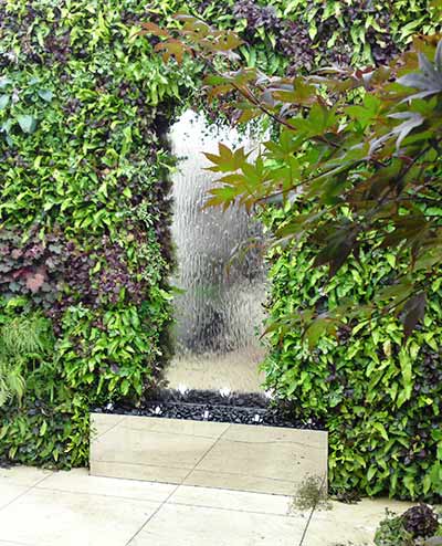 Stainless steel water wall surrounded by planting